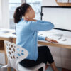 Shot of a businesswoman experiencing back pain while working at her desk in a modern office.
