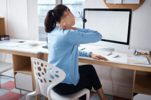 Shot of a businesswoman experiencing back pain while working at her desk in a modern office.