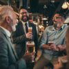 Team of colleagues socializing at the bar and drinking beers alcohol