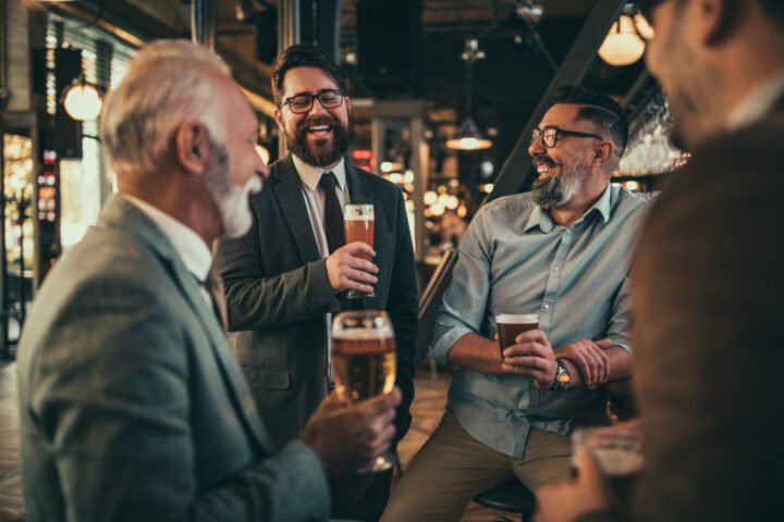 Team of colleagues socializing at the bar and drinking beers alcohol