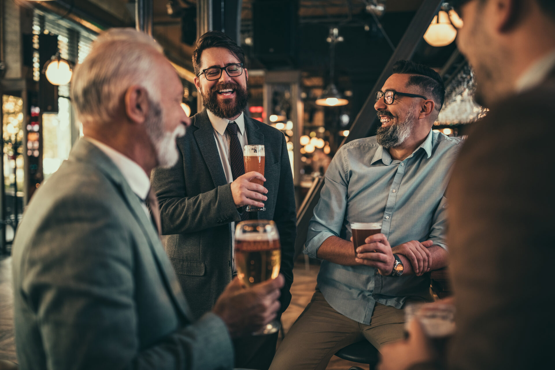 Team of colleagues socializing at the bar and drinking beers alcohol