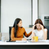 woman comforts her distressed coworker in office. Concept of workplace stress, burnout, empathy, and emotional support in professional environments.