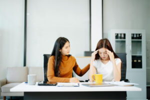 woman comforts her distressed coworker in office. Concept of workplace stress, burnout, empathy, and emotional support in professional environments.