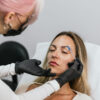 Skilled aesthetician performs precise eyebrow tattooing on a client in a modern salon