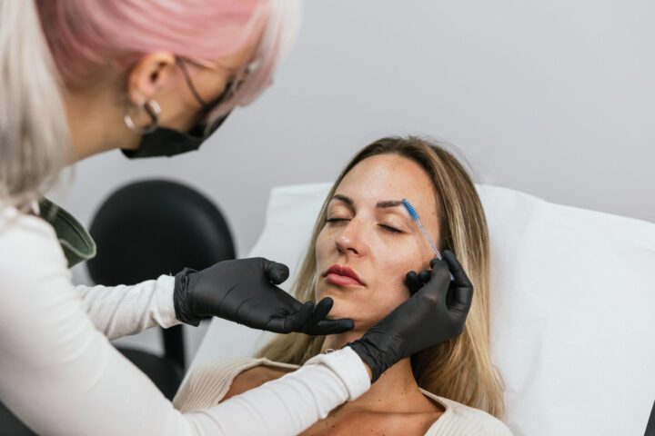 Skilled aesthetician performs precise eyebrow tattooing on a client in a modern salon