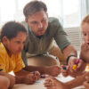 Portrait of young male teacher working with kids drawing pictures while having fun in pre school or development center