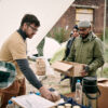 Bearded volunteer in yellow tshirt standing in food tent and giving food to refugees