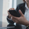 Close up, business woman using mobile phone at modern office. Businesswoman hand holding smartphone, surfing the internet, social media networking with copy space