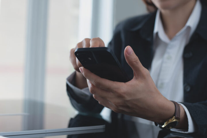 Close up, business woman using mobile phone at modern office. Businesswoman hand holding smartphone, surfing the internet, social media networking with copy space