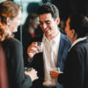 Business professionals gather after work for drinks and casual conversation. A relaxed office party moment showing teamwork, connection, and positive workplace culture in a corporate environment.