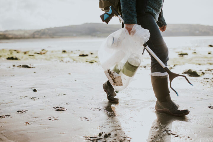 Beach cleanup volunteer carrying garbage bag for environment campaign