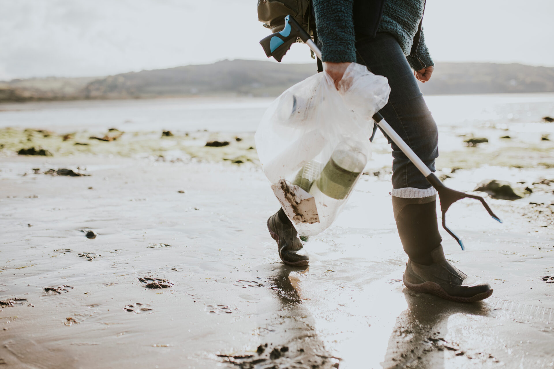 Beach cleanup volunteer carrying garbage bag for environment campaign