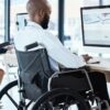 Wheelchair, office and black man disability in the workplace doing business analyst work. Working, computer and desk job of a disabled worker back planning a digital strategy for inclusive job.